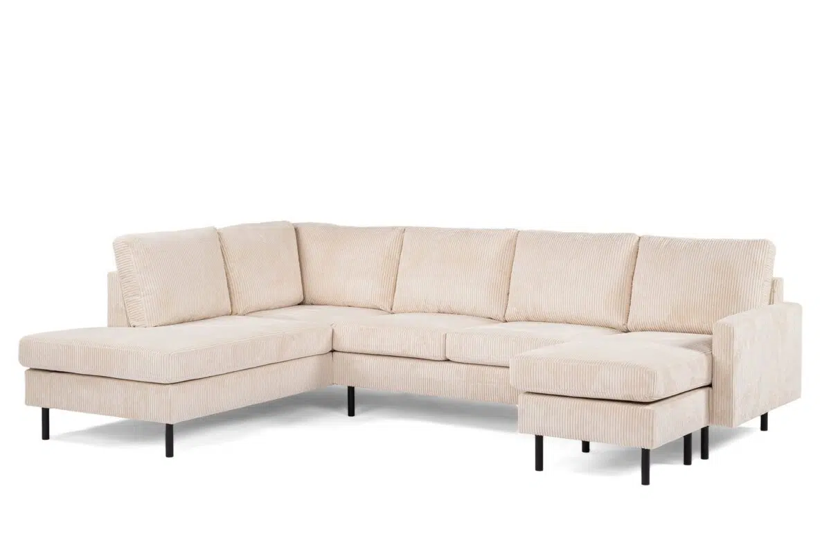 Een beige, L-vormige sectionele bank met corduroy stof en zwarte poten. Het ontwerp omvat een chaise longue aan de linker- en rechterkant, wat zorgt voor voldoende zitruimte. De bank is modern en ruim, geschikt voor een woonkamer.