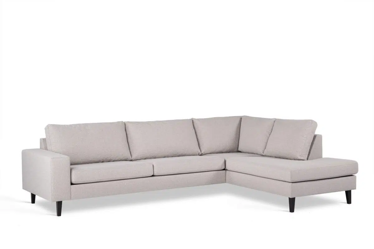 Een lichtgrijze L-vormige sectionele bank met drie zitkussens en bijpassende rugkussens. Het heeft strakke lijnen, een modern design en donkere houten poten, tegen een effen witte achtergrond.