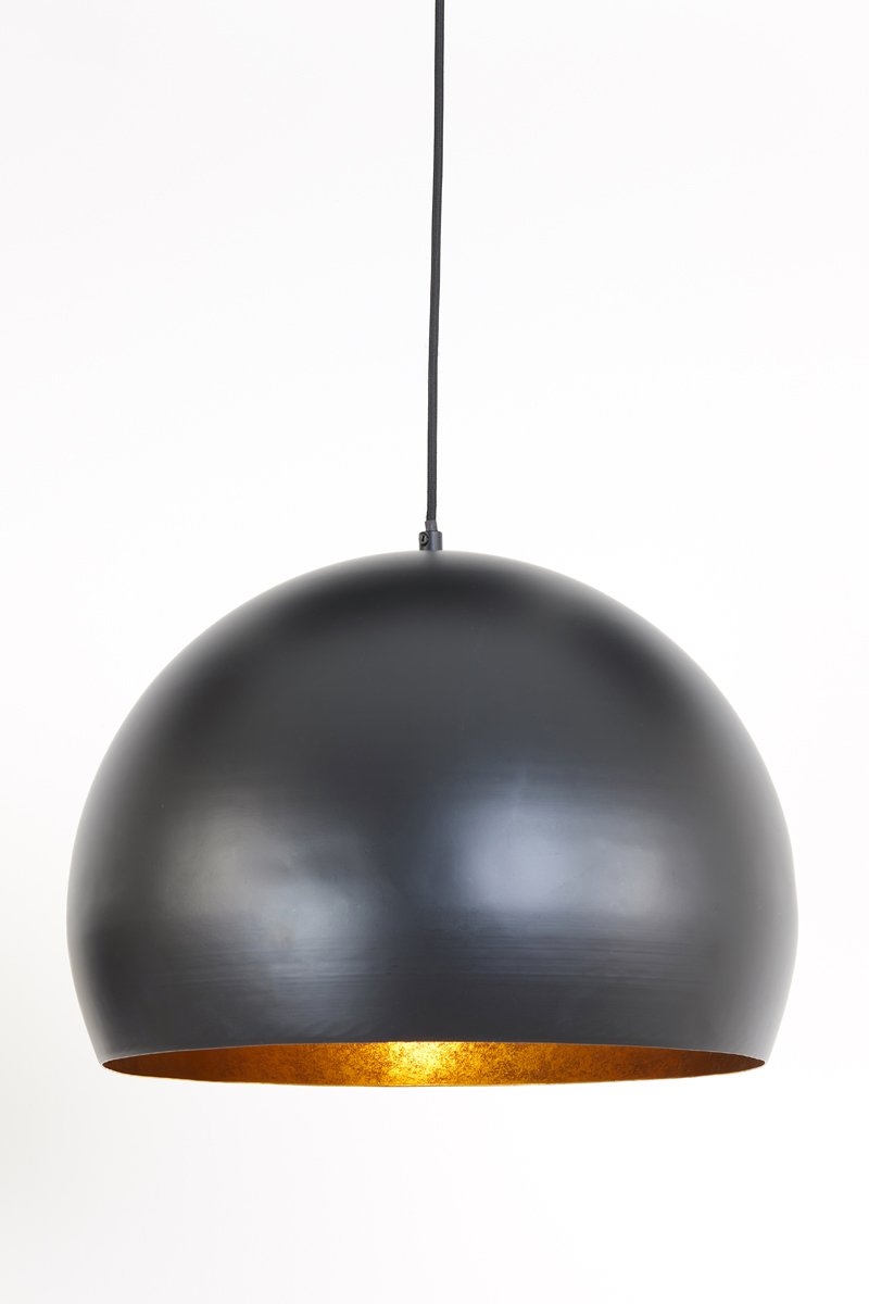 Een zwarte, koepelvormige hanglamp hangt aan een snoer tegen een witte achtergrond. De binnenkant van de lamp is goudkleurig, met een warm licht dat van binnenuit schijnt.