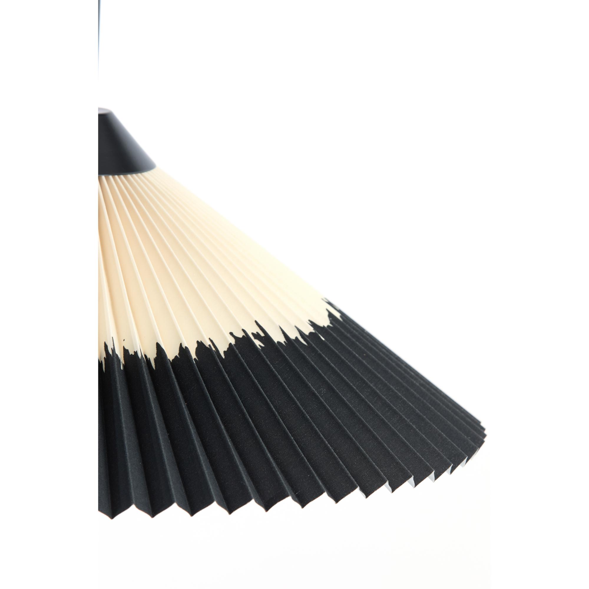 Close-up van een geplooide lampenkap met een tweekleurig ontwerp, met een gradiënt van beige aan de bovenkant naar zwart aan de onderkant. Het unieke patroon lijkt op potloodstreken, wat een artistieke en moderne esthetiek creëert.