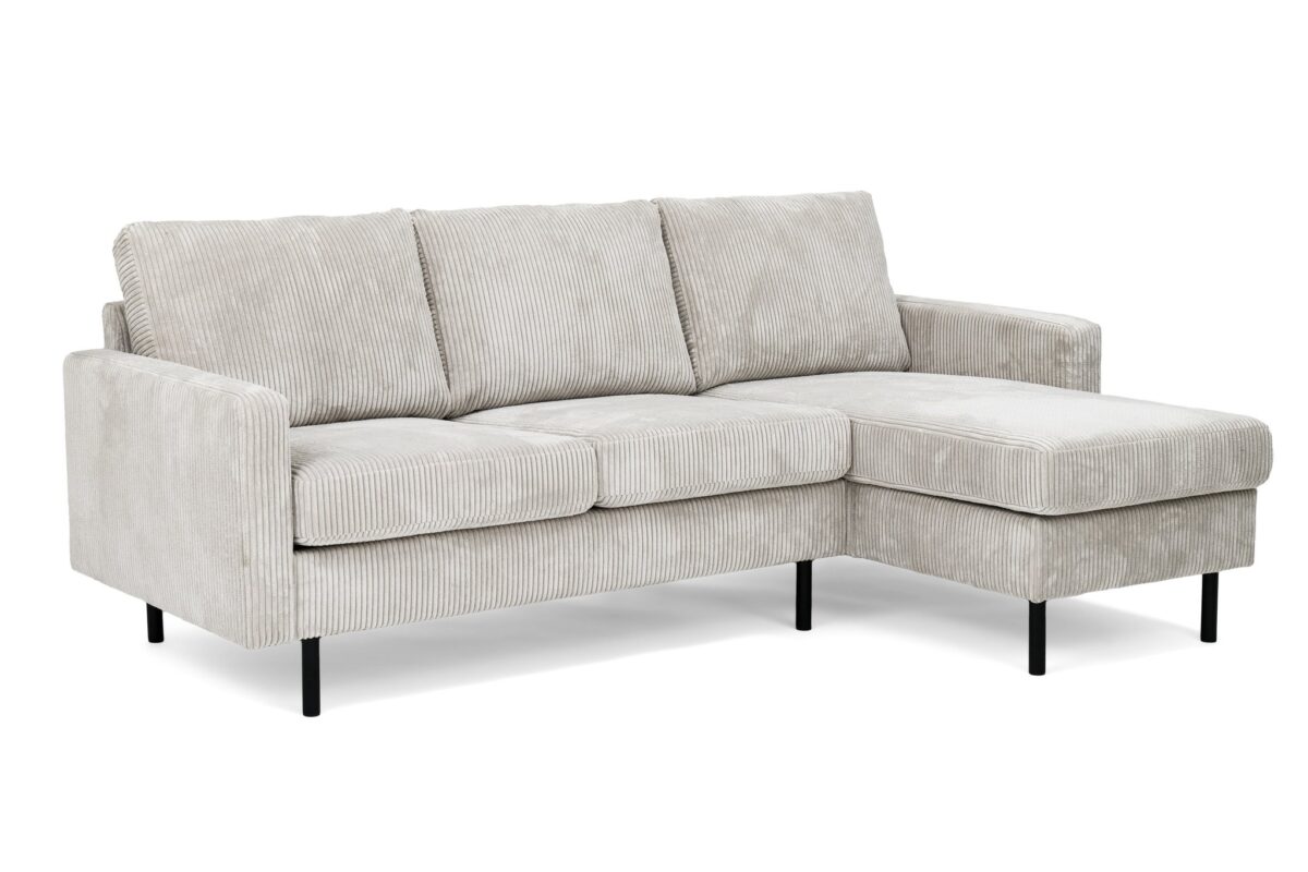 Een lichtgrijze, corduroy-look sectionele bank met een chaise longue aan de linkerkant. Het heeft drie rugkussens en twee zitkussens, ondersteund door dunne zwarte metalen poten. De stof heeft een subtiele gestreepte textuur.