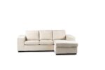 Een beige sectionele bank met drie gestoffeerde zittingen en een chaise longue aan de rechterkant, tegen een effen witte achtergrond. De bank heeft brede armleuningen en staat op korte zwarte poten.