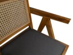 Close-up van een houten stoel met een geometrisch armleuningontwerp, een geweven rieten rugleuning en een donkere, gewatteerde zitting. Het gedetailleerde vakmanschap benadrukt de natuurlijke houtstructuur en het ingewikkelde rietpatroon tegen een witte achtergrond.