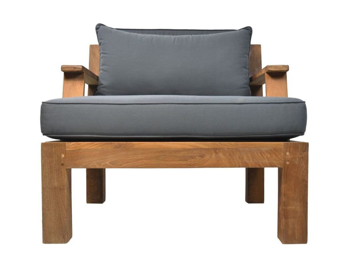 Een houten fauteuil met een eenvoudig, modern design met een dik grijs kussen op de zitting en een bijpassend grijs rugkussen. De stoel heeft brede, platte armleuningen en een stevig rechthoekig frame.