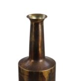 Een hoge, cilindrische, vintage messing vaas met een smalle hals en een brede, platte basis. De vaas heeft een donkere, verouderde patina met een licht reflecterend oppervlak. De bovenste opening is rond en uitlopend.