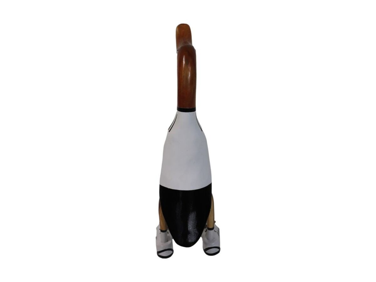 Een gesneden houten pinguïnsculptuur met een bruine kop, wit lichaam en zwarte onderkant, gestileerd om te lijken alsof hij een pak draagt. De pinguïn staat rechtop, met zijn gezicht naar achteren tegen een effen witte achtergrond.