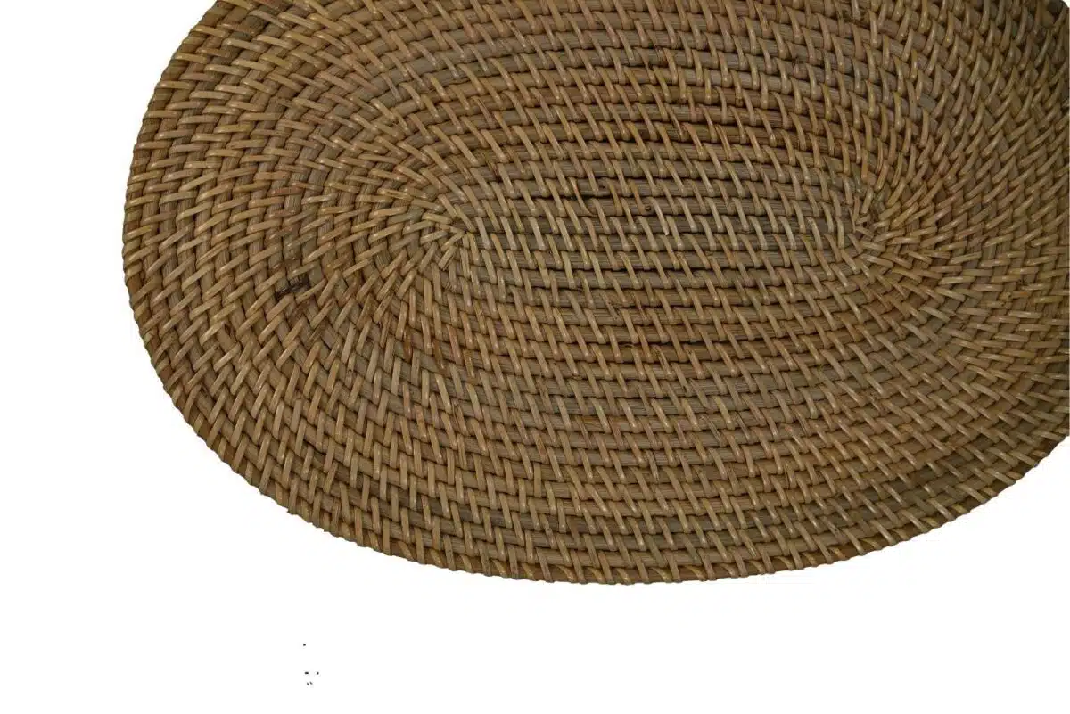 Ovaalvormige, gevlochten rotanmat op een witte achtergrond, met een ingewikkelde, natuurlijke textuur.