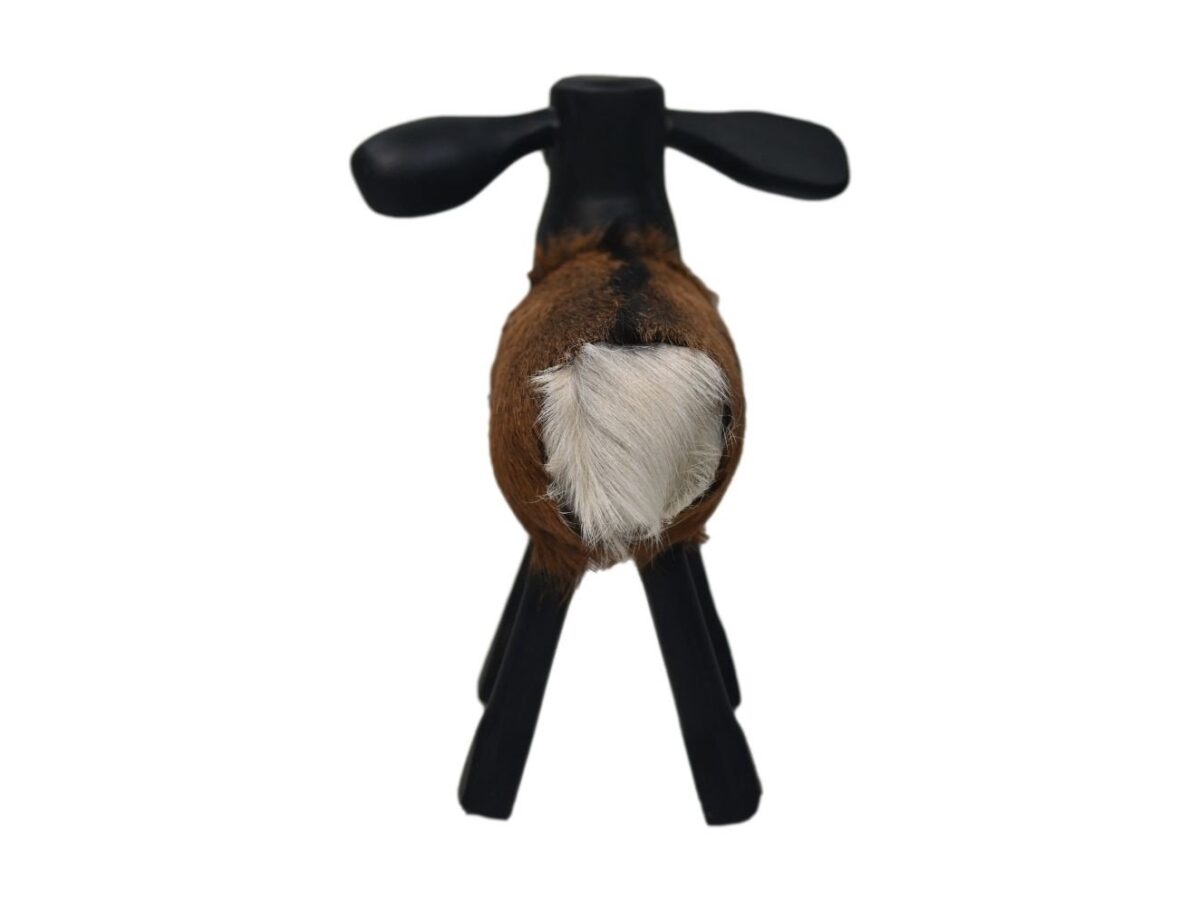 Een klein, bruin en zwart houten hondenbeeldje dat op vier poten staat, van achteren bekeken. Het beeldje heeft een donzige witte staart en zijn kop is lichtjes naar beneden gekanteld, tegen een effen witte achtergrond.