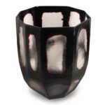 Een gefacetteerd, metalen beeldhouwwerk met een reflecterende, achthoekige vorm en een donker oppervlak met lichtere, ongelijke plekken. Het stuk heeft een modern, abstract ontwerp met gladde randen en een getextureerd uiterlijk.