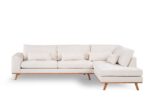 Beige L-vormige hoekbank met houten poten, drie zitkussens, diverse rechthoekige rugkussens en een chaise longue aan de rechterkant, tegen een witte achtergrond.