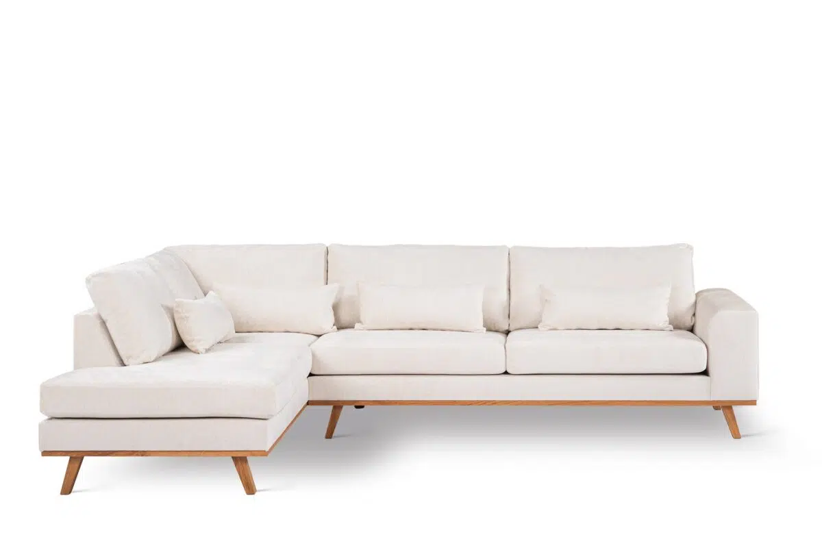 Een moderne L-vormige beige sectionele bank met houten poten en armleuningen, met zachte zit- en rugkussens. Inclusief extra rechthoekige en verstevigde kussens, tegen een effen witte achtergrond.