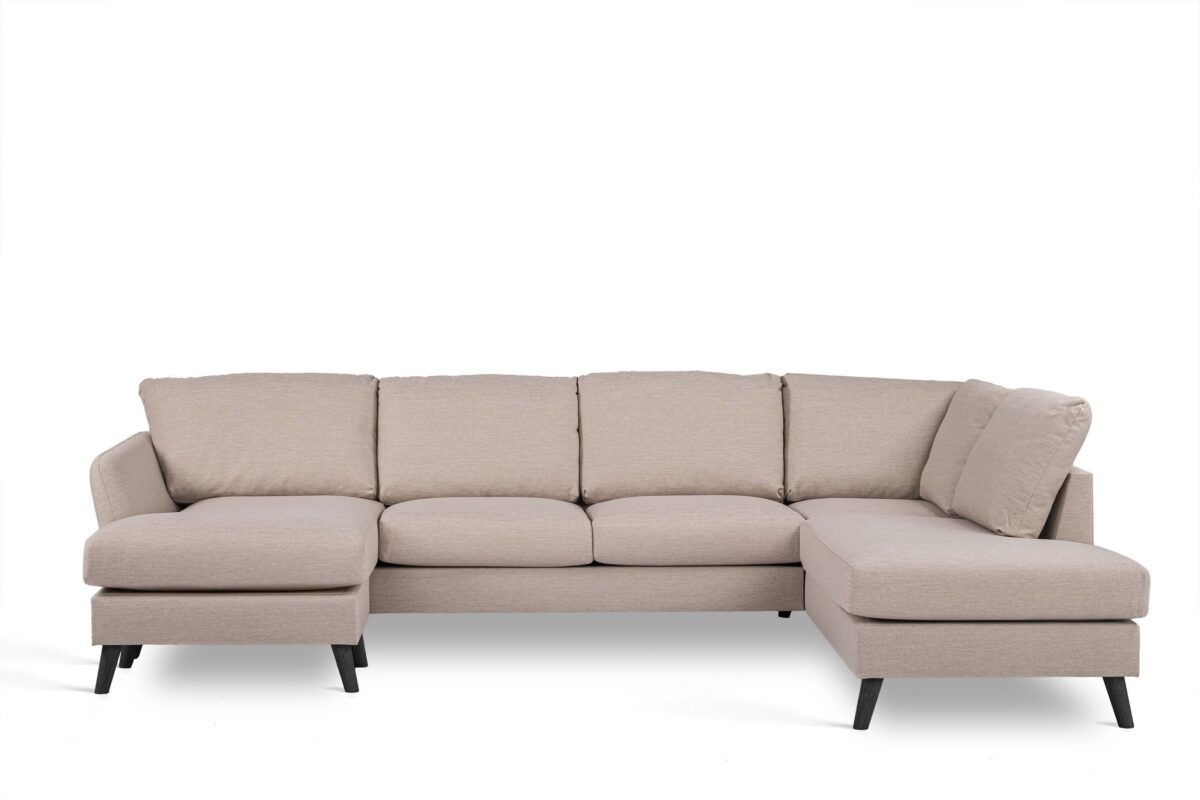 Een beige L-vormige sectionele bank met zwarte poten. De bank heeft vijf gestoffeerde zittingen en een chaise longue aan de linkerkant. Het ontwerp is modern en geschikt voor een woonkamer.