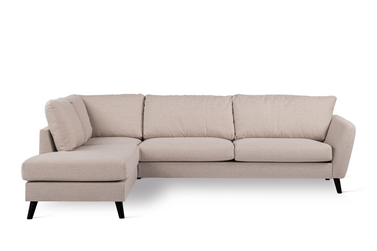 Beige L-vormige sectionele bank op een witte achtergrond. De bank heeft drie grote zitkussens en een chaise longue aan de linkerkant, ondersteund door strakke zwarte poten.