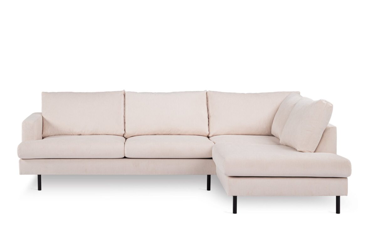 Een lichtbeige L-vormige sectionele bank met drie gestoffeerde zittingen aan de linkerkant en een chaise longue aan de rechterkant. Het heeft zwarte, slanke poten en een minimalistisch ontwerp, tegen een effen witte achtergrond.