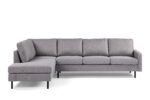 Een moderne, grijze sectionele bank met een chaise longue aan de linkerkant. Het heeft strakke lijnen, zachte kussens en wordt ondersteund door zwarte poten. De bank staat tegen een effen witte achtergrond.