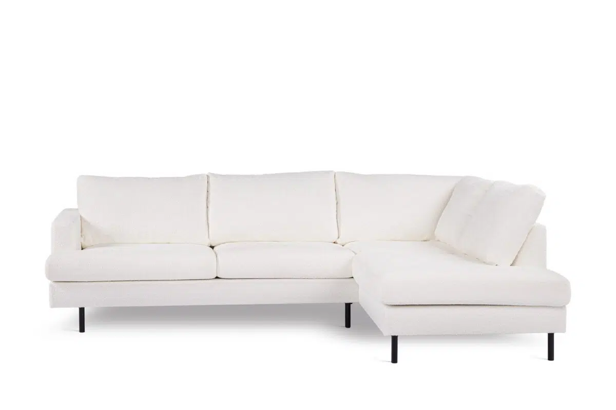 Een moderne witte sectionele bank met een minimalistisch design, met een driezitsgedeelte en een aangebouwde chaise longue aan de rechterkant. De bank heeft zwarte metalen poten en zachte, vierkante kussens, tegen een effen witte achtergrond.