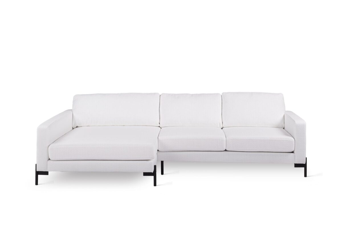 Een moderne witte sectionele bank tegen een effen witte achtergrond. Het heeft drie gestoffeerde zittingen en een chaise longue aan de linkerkant. De bank heeft strakke lijnen en zwarte metalen poten.