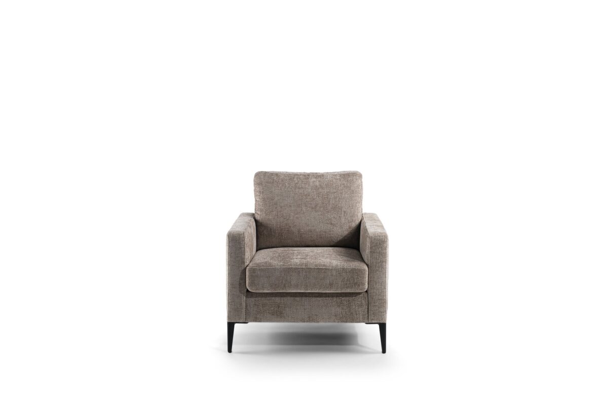 Een grijze, moderne fauteuil met vierkante armleuningen en een gewatteerde zitting, geplaatst tegen een witte achtergrond. De stoel heeft korte, zwarte poten.