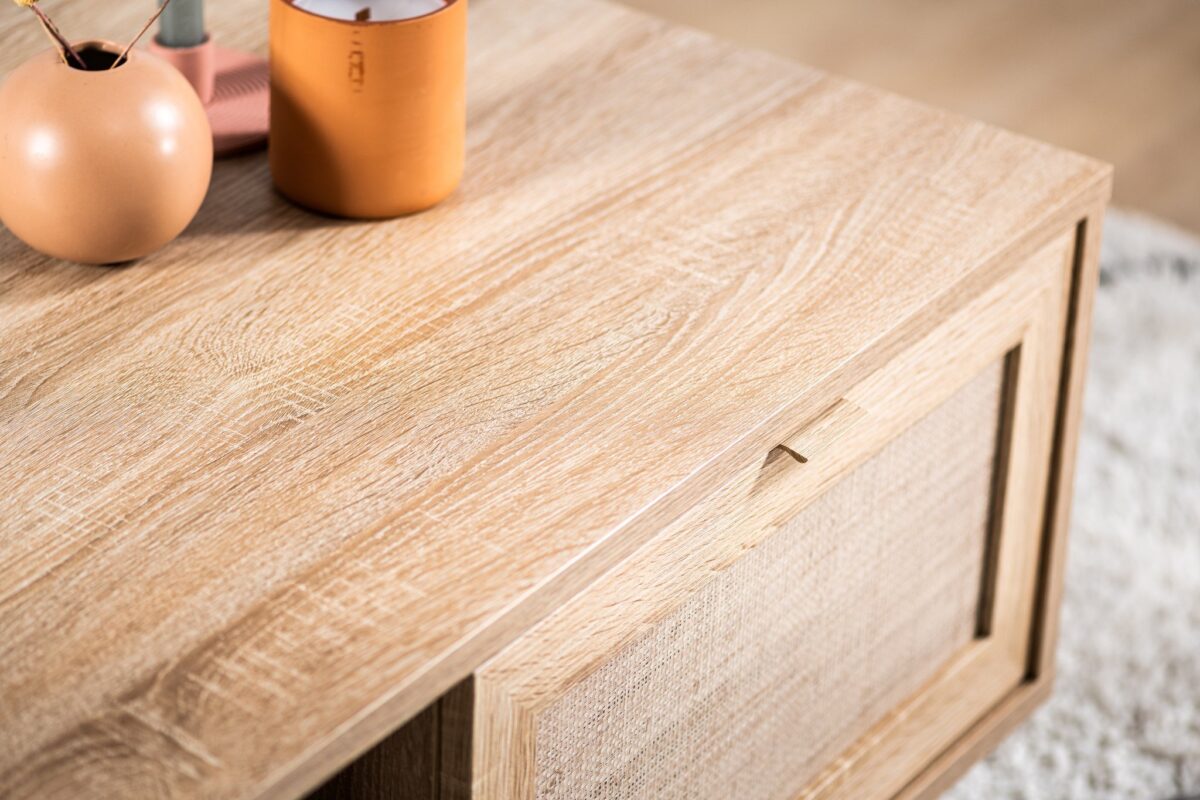 Close-up van de Salontafel, 100x60 cm, M930 Sedona met een gestructureerd licht houten oppervlak, met daarop een vaas en een oranje beker. Naast de tafel is een beige tapijt zichtbaar.