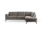Een moderne L-vormige bank, "3 zits hoek rechts" in Perfect Harmony 04 stof (R720 champagne), heeft drie linker zitkussens en een rechter chaise, tegen een witte achtergrond met slanke zwarte metalen poten.