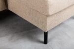 Close-up van de hoek van de 3 zits bank CL L+R in D460 beige stof met zwarte metalen poten, getoond op een lichtgrijze betonnen vloer.
