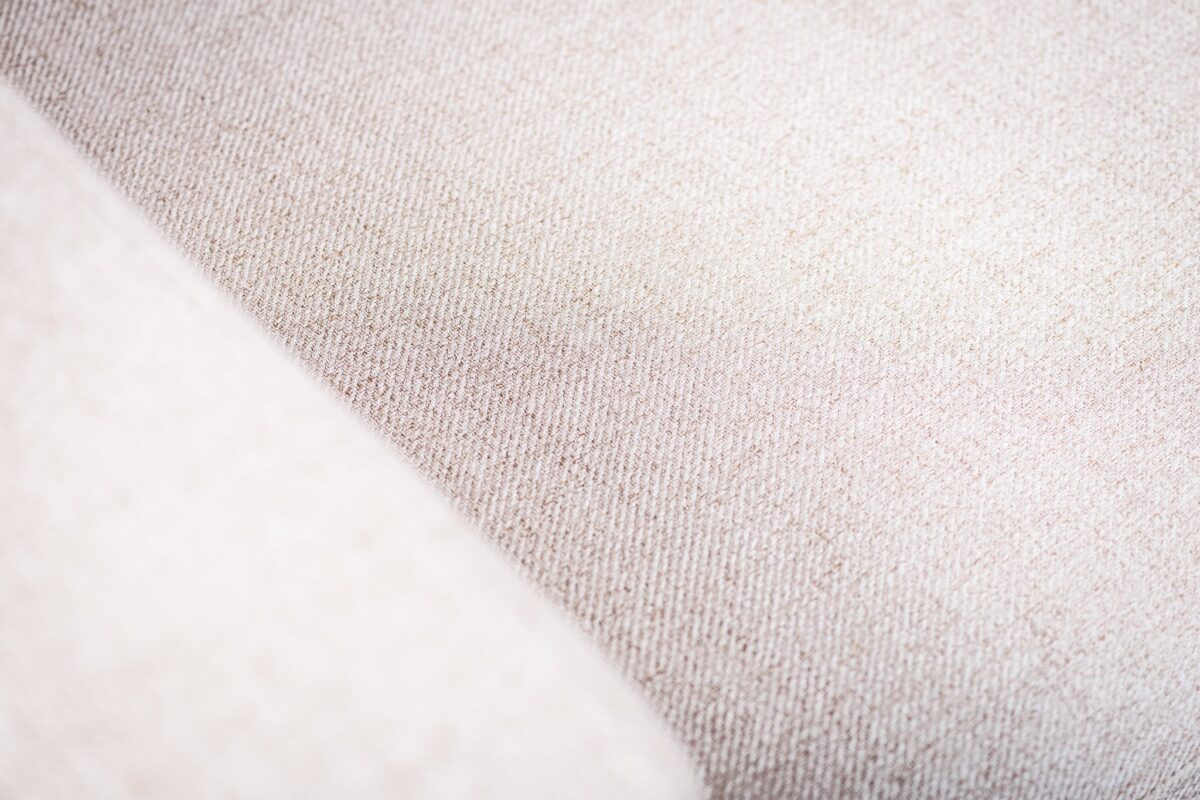 Close-up van de 3 zits bank CL L+R in Chloe C460 beige stof, die de zachte, geweven textuur en diagonale naad laat zien. Zachte verlichting benadrukt de kalme, neutrale look van deze ietwat grove bekleding.