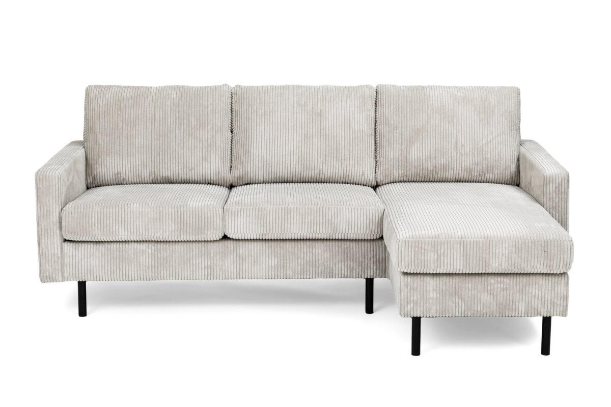 Een moderne, lichtgrijze corduroy sectionele bank met een chaise longue aan de rechterkant. De bank heeft drie rugkussens en rust op zwarte metalen poten, wat hem een strak en minimalistisch design geeft.