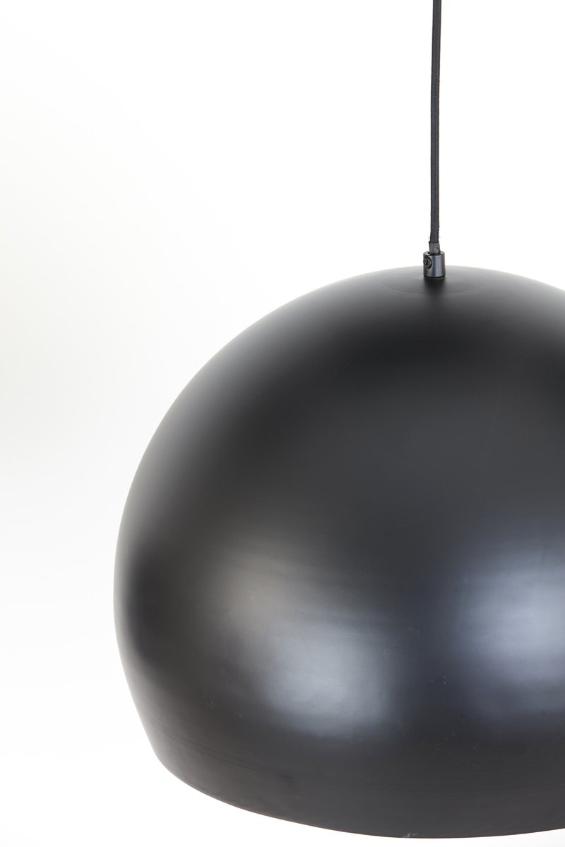 Een close-up van een matte zwarte koepelvormige hanglamp die tegen een witte achtergrond hangt. Het eenvoudige ontwerp van de lamp heeft een glad oppervlak en een zichtbaar zwart snoer dat van bovenaf uitsteekt.