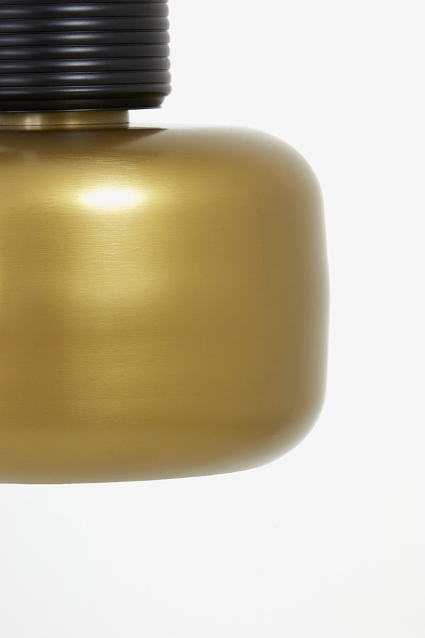 Close-up van een moderne, minimalistische lamp met een gladde, cilindrische gouden metalen basis en een gesegmenteerde zwarte bovenkant. De afbeelding is bijgesneden om slechts een deel van de lamp te tonen tegen een effen witte achtergrond.
