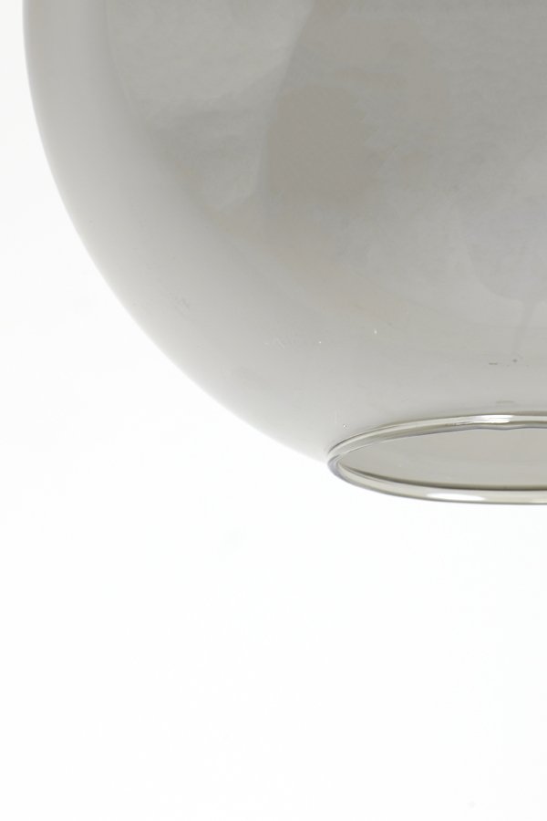 Close-up van de onderkant van een transparante glazen lampenkap met een gebogen oppervlak tegen een witte achtergrond. Het glas lijkt glad en licht reflecterend, met een metalen rand zichtbaar aan de onderkant van de kap.