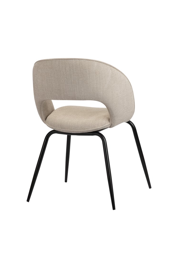 Een moderne stoel met een beige, gebogen stoffen rugleuning en zitting, met een uitsparing. Het heeft een strak uiterlijk met vier slanke zwarte metalen poten. De stoel wordt bekeken vanuit de achterste rechterhoek.