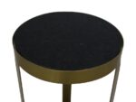 Een kleine ronde bijzettafel met een zwart tafelblad en gouden metalen poten. De tafel heeft een strak, minimalistisch design en is gefotografeerd tegen een witte achtergrond.