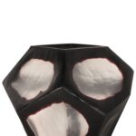 Een geometrisch, metalen, gefacetteerd object met zwarte en reflecterende zilveren oppervlakken, dat lijkt op een abstract beeldhouwwerk. Het oppervlak heeft drie prominente zilveren gebieden met onregelmatige vormen. De achtergrond is effen wit.
