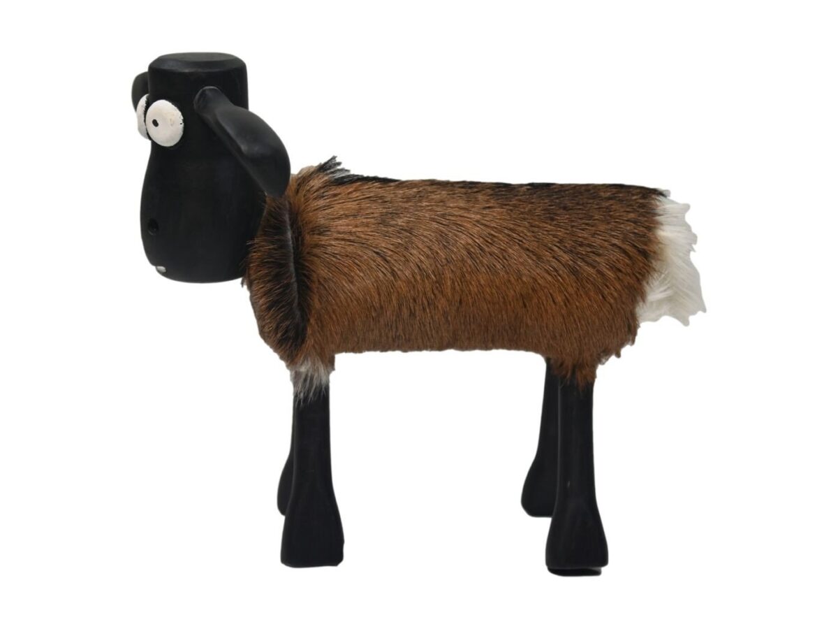 Een speelgoedfiguurtje van een schaap met een harige bruine en witte vacht, zwarte kop en poten en grote, ronde ogen. Het beeldje is naar links gericht en toont een simplistisch, speels ontwerp.