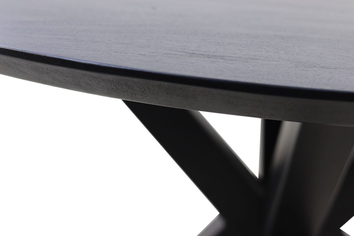 Close-up van de rand van een zwarte houten tafel en een deel van de strakke zwarte metalen poten, die een X-vorm vormen. De achtergrond is wit, wat het moderne ontwerp en de contrasterende texturen van de tafel benadrukt.