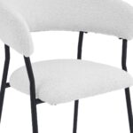 Een close-up van een moderne stoel met een witte, getextureerde stoffen zitting en rugleuning, ondersteund door strakke zwarte metalen poten. Het ontwerp is minimalistisch en eigentijds.