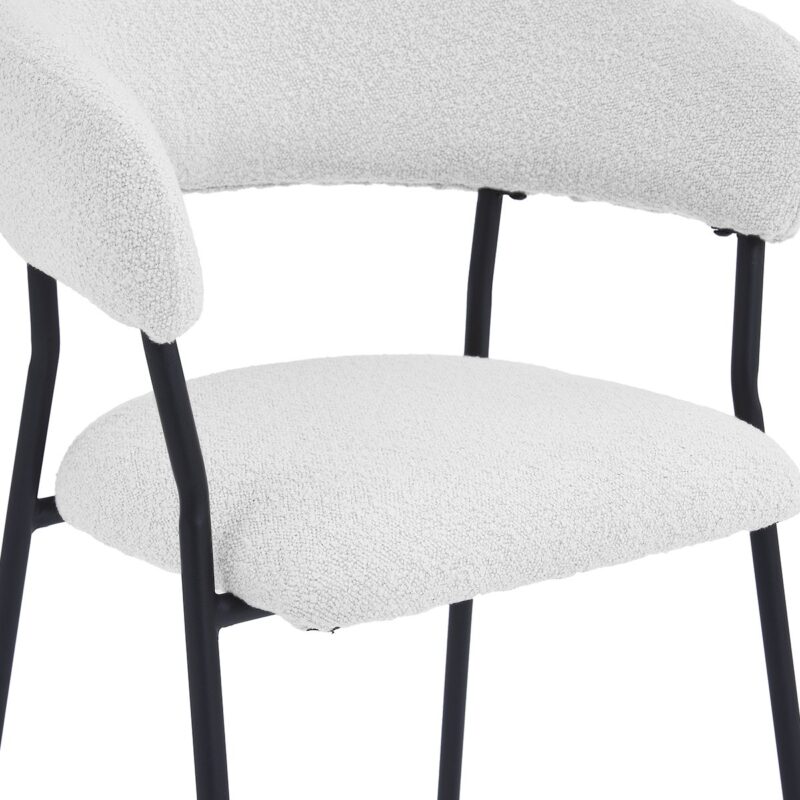 Een close-up van een moderne stoel met een witte, getextureerde stoffen zitting en rugleuning, ondersteund door strakke zwarte metalen poten. Het ontwerp is minimalistisch en eigentijds.