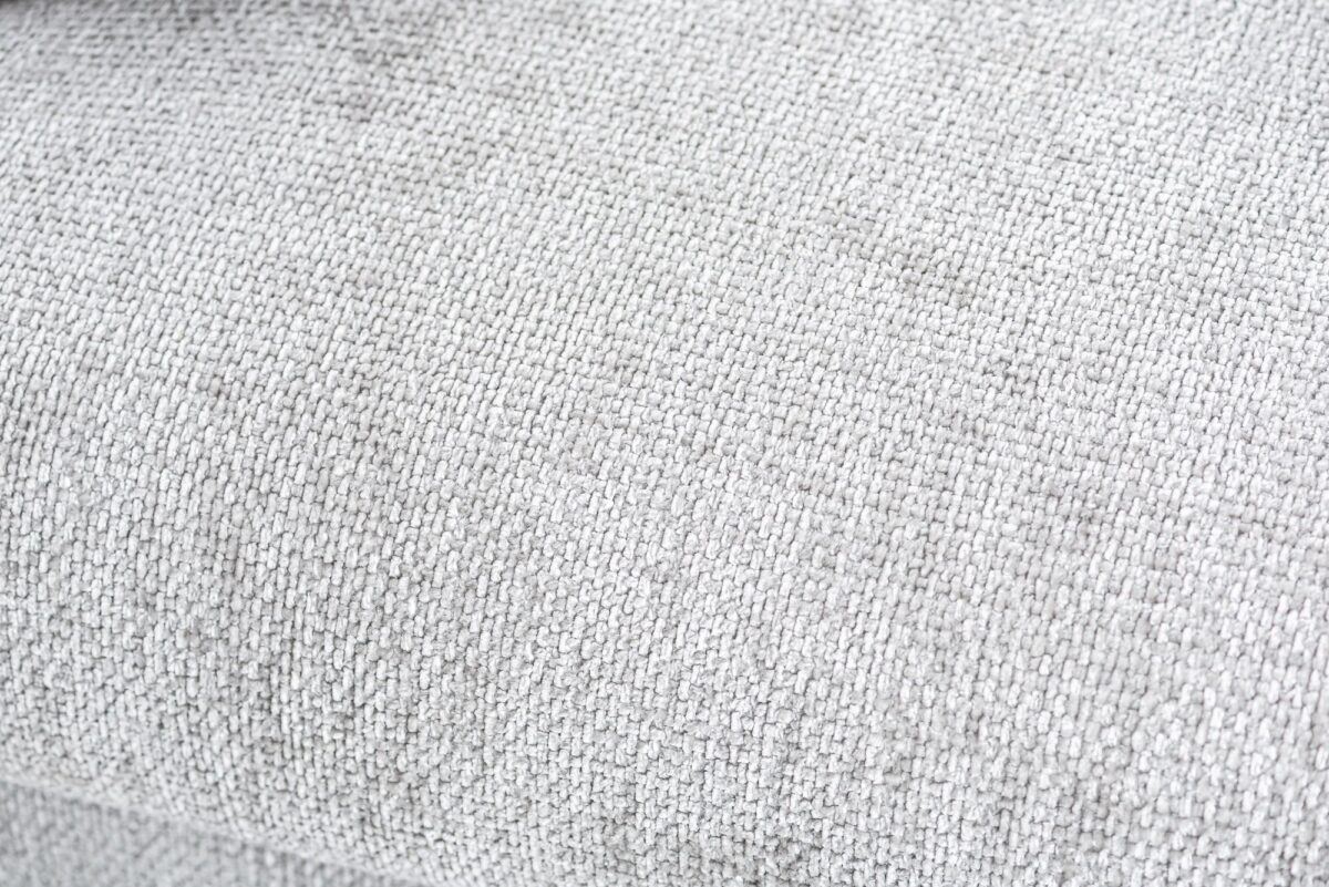 Close-up van grijze geweven stoffentextuur, die de fijne details van het verweven patroon van de textiel laat zien. Het materiaal lijkt zacht en licht getextureerd, met een subtiele glans die van het oppervlak afstraalt.