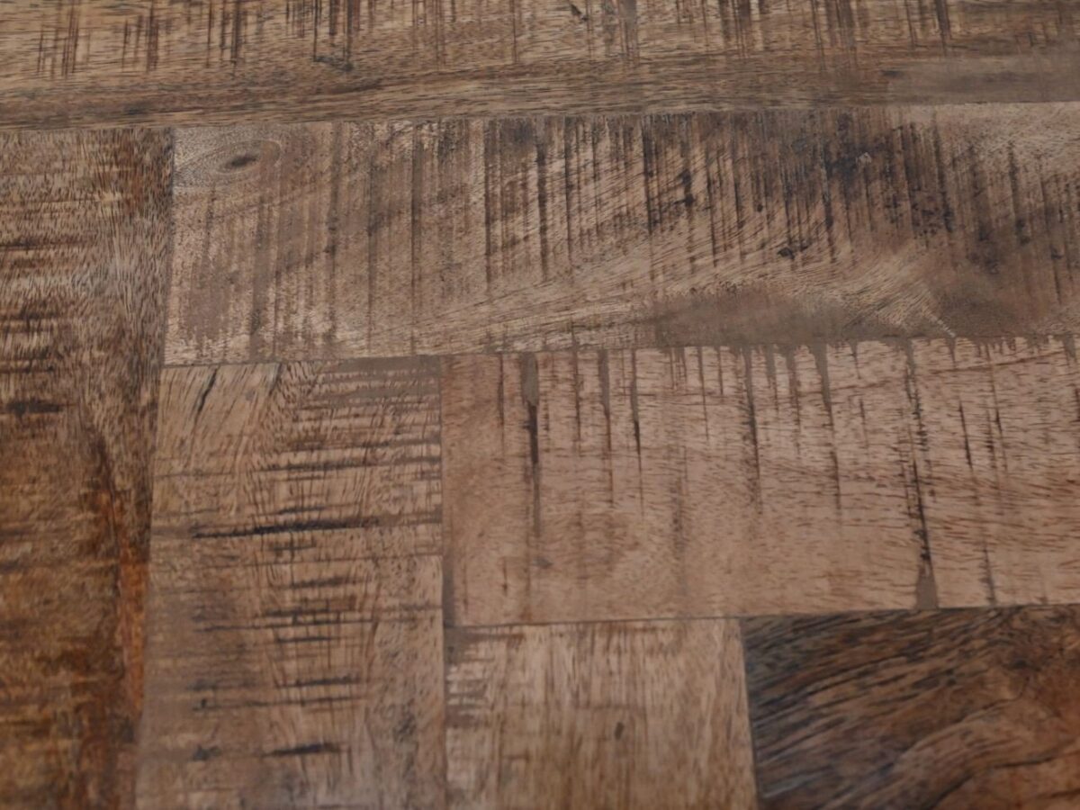 Close-up van een houten oppervlak met een visgraatmotief. De textuur toont natuurlijke nerven en verschillende tinten bruin, wat het een rustieke uitstraling geeft. Het hout vertoont wat verwering en slijtplekken, wat bijdraagt aan het karakter.