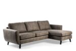 De 3 zits bank CL L+R, bekleed met Savannah S520 taupe stof en voorzien van drie zitkussens, een chaise lounge rechts en zwarte tapse poten, schittert voor een witte achtergrond.
