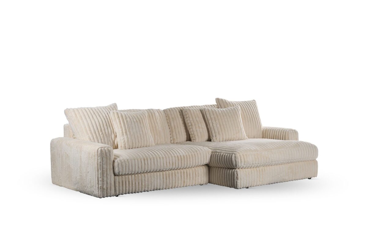 De 3 zits bank CL L+R, stof Vito 23, D460 beige is een beige corduroy sofa met brede armleuningen, zes bijpassende rugkussens en een chaise lounge aan de rechterkant, getoond op een witte achtergrond.