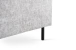 Close-up van de onderste hoek van de 3 zits hoek links, stof Haga 08, E920 naturel met de lichtgrijze structuurstof en enkele zwarte metalen cilindervormige poot tegen een witte achtergrond.