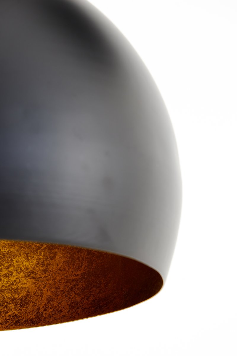 Close-up van een matte, zwarte koepelvormige lamp tegen een witte achtergrond, met een binnenkant met een warme, goudkleurige structuur.