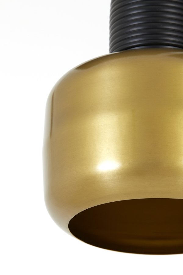 Close-up van een moderne, cilindrische lamp met een glanzend messing exterieur en een geribbelde, zwarte bovenkant. De afbeelding legt het onderste deel van de lamp vast tegen een witte achtergrond.
