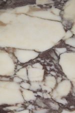 Close-up van een marmeren oppervlak met een patroon van crèmewitte en donkerbruine aderen. De textuur is glad en de aderen creëren een abstract, natuurlijk ontwerp over de steen.