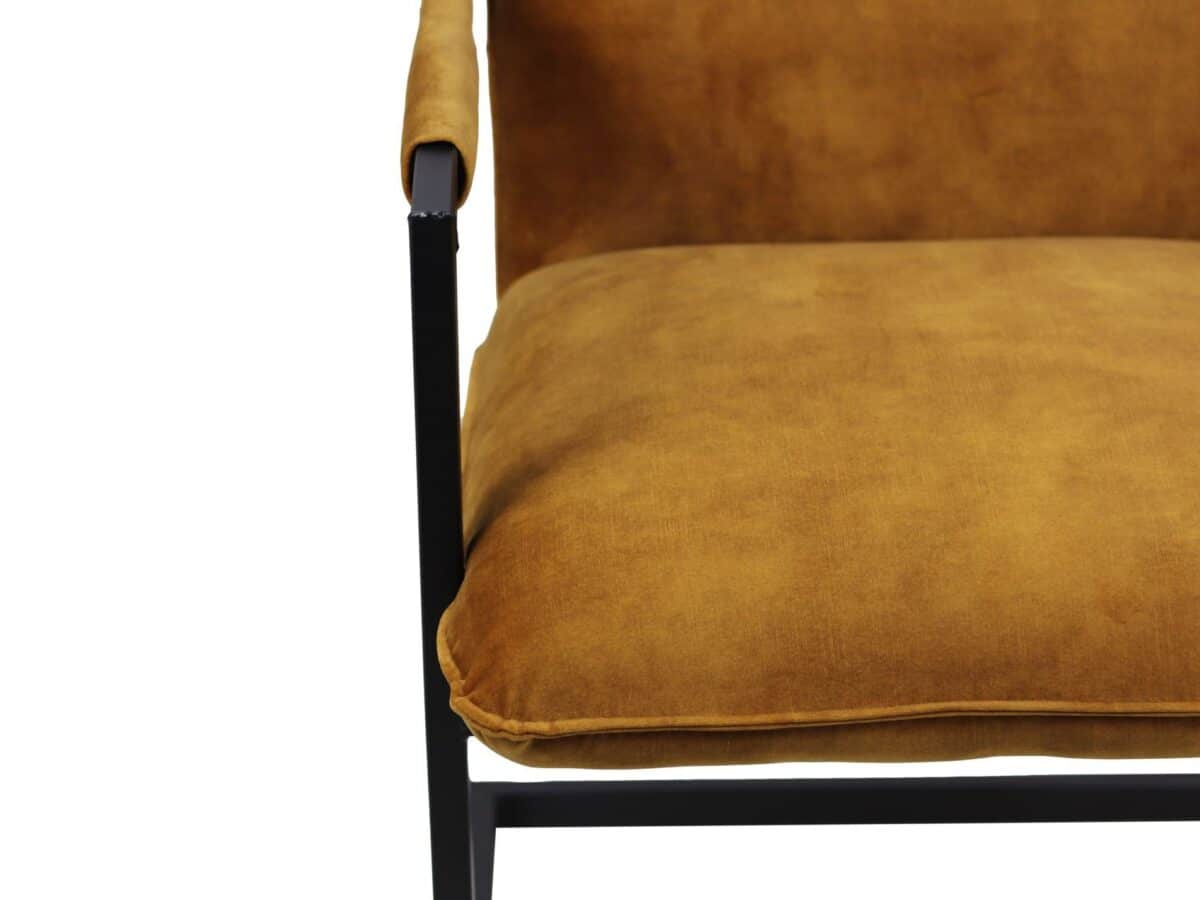Close-up van een stoel met een mosterdgeel kussen en een zwart metalen frame. De armleuning en zitting zijn prominent zichtbaar, wat het moderne design en het kleurcontrast van de stoel benadrukt.