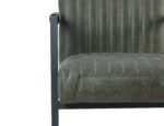 Close-up van een stoel met donkergroene, verticaal gestikte bekleding. De stoel heeft een zwart metalen frame en armleuning, wat een modern design laat zien. De textuur van de stof is zichtbaar, wat het een licht verweerde uitstraling geeft.