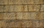 Close-up van strak geweven strotouwen gerangschikt in parallelle rijen, waardoor een getextureerd patroon ontstaat. De natuurlijke vezels variëren in tinten beige en lichtbruin, wat een rustieke en handgemaakte uitstraling geeft.