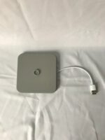 Een vierkante grijze oplaadpad met een gecentreerde knop ligt op een wit stoffen oppervlak. Een korte witte USB-kabel is bevestigd aan de zijkant van de pad.