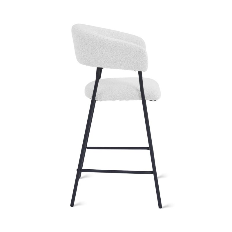 Moderne barkruk met een witte, getextureerde zitting en rugleuning, ondersteund door een strak zwart metalen frame. De kruk heeft een minimalistisch ontwerp, met een zijaanzicht met een ronde voetensteun die de poten verbindt.